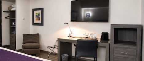 Une chambre d’hôtel comprenant un lit, un bureau avec une chaise, une télévision, une armoire et une poubelle.