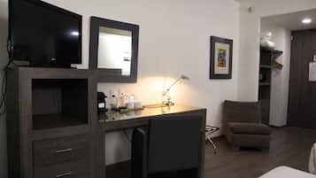 A hotel room with a desk, chair, television, and a bed.