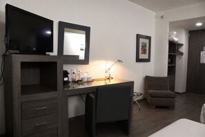 Une chambre d’hôtel équipée d’un bureau, d’une chaise, d’une télévision et d’un lit.