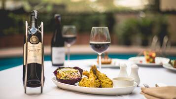 Una mesa de comedor con una botella de vino, una copa de vino y platos de comida.
