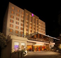 A multi-story hotel with a prominent entrance, a covered walkway, and a parking area.