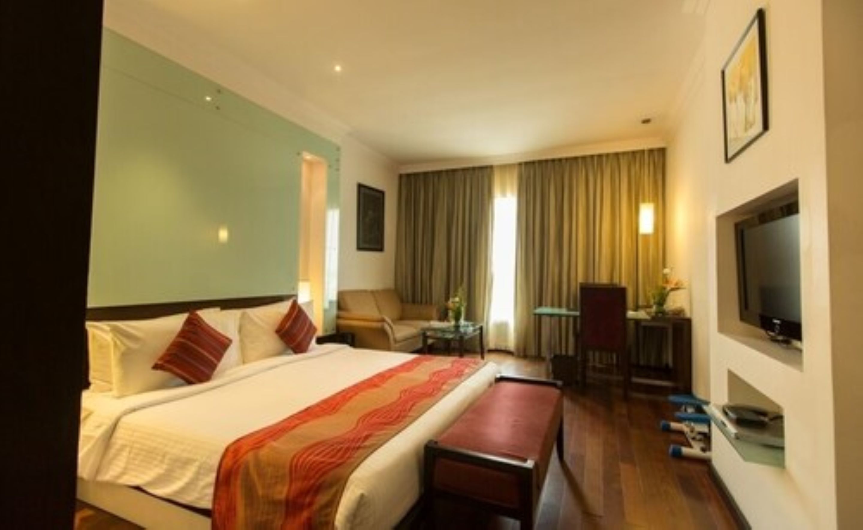 A hotel room with a bed, a desk, a chair, a television, and a window with curtains.