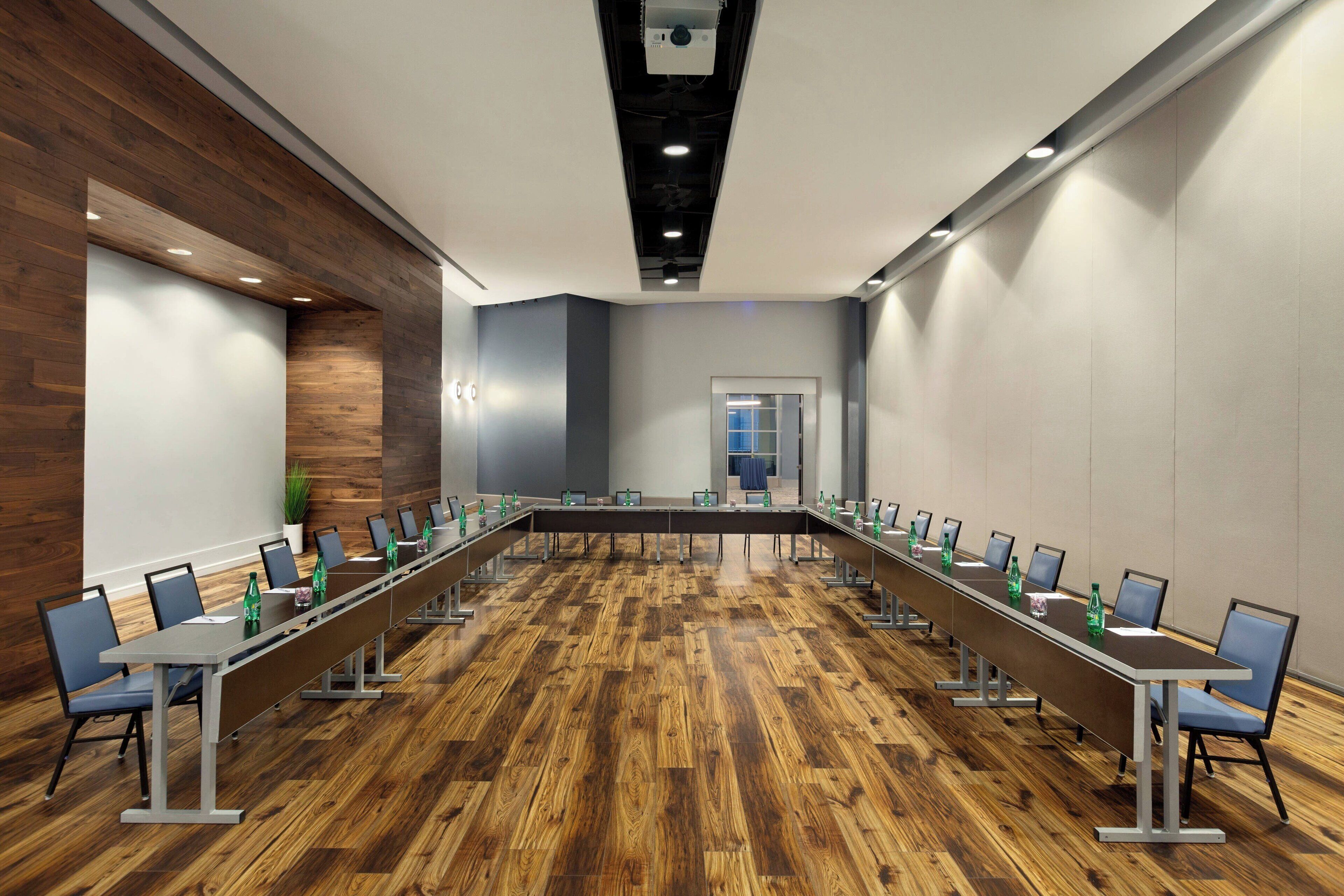 A conference room with a long table, chairs, and a wooden floor.