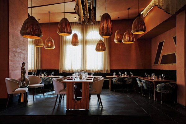 Un restaurante con varias mesas, sillas e iluminación colgante.