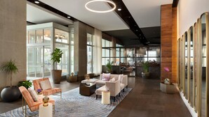 A spacious lobby with a modern sofa set, a coffee table, and a large potted plant. - Twelve Midtown, Autograph Collection (Atlanta)