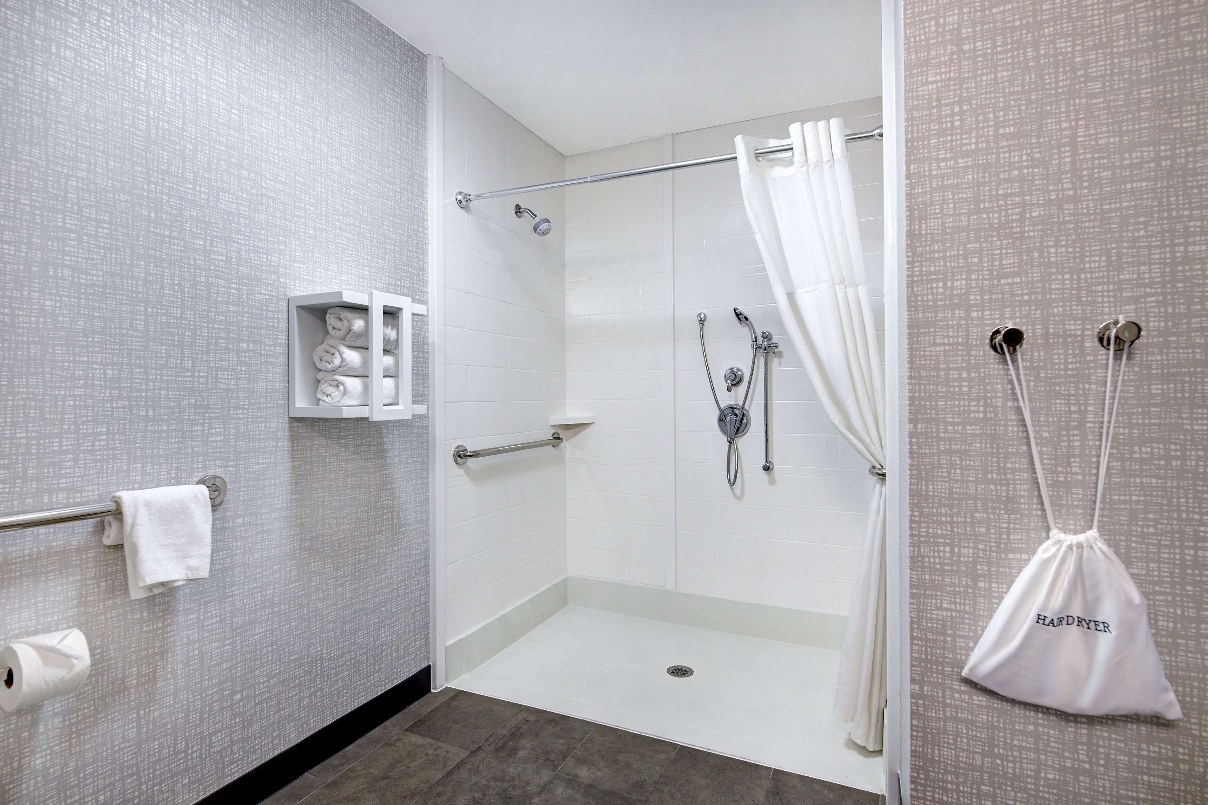 Un baño moderno con ducha a nivel, un perchero y un secador de manos.