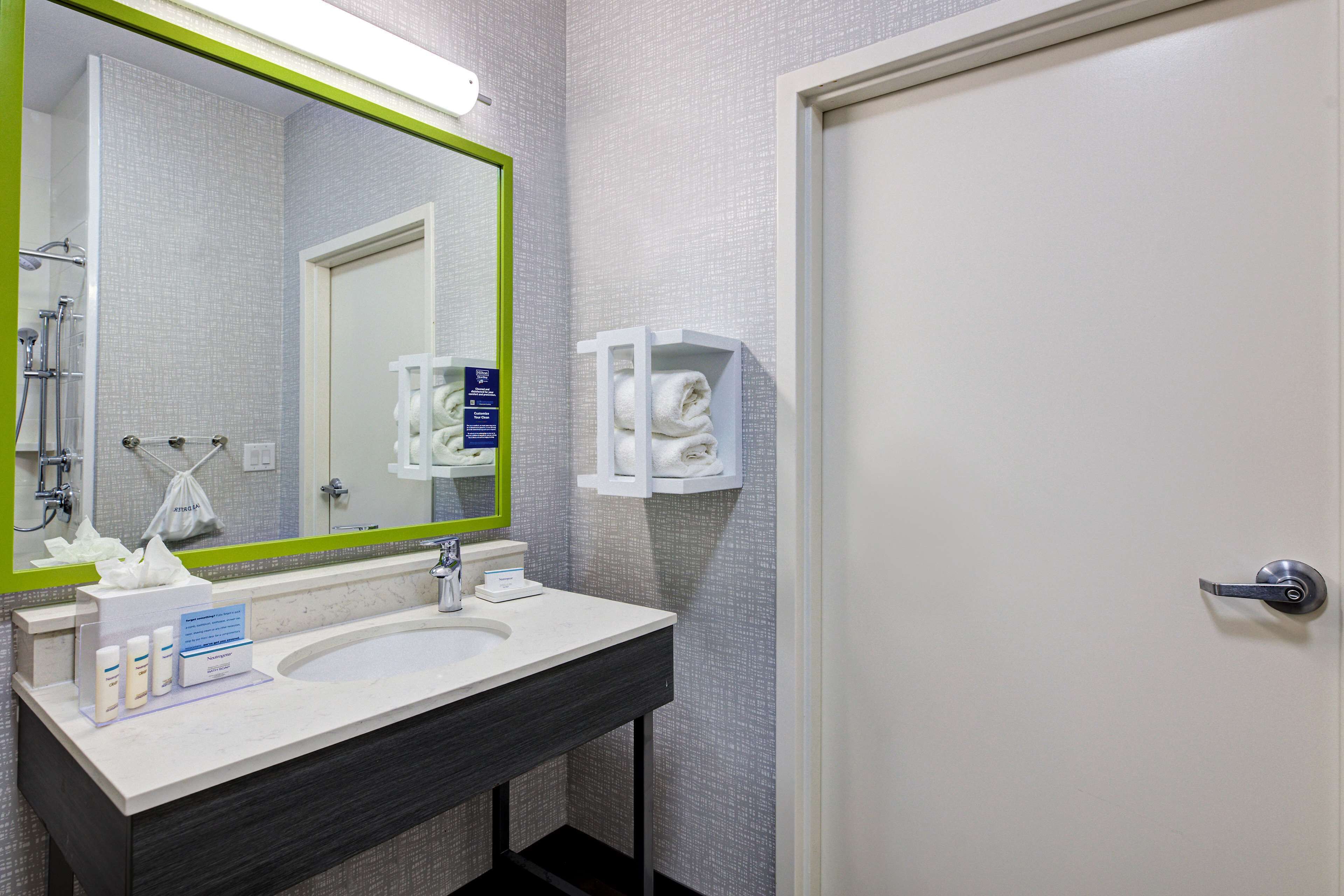 A bathroom with a white sink, a mirror with a green frame, and a towel rack.