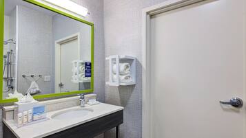 A bathroom with a white sink, a mirror with a green frame, and a towel rack.