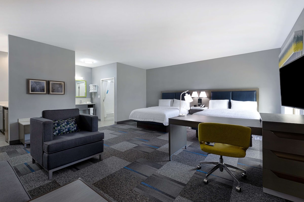A hotel room with a bed, a desk, a chair, a sofa, and a small table.