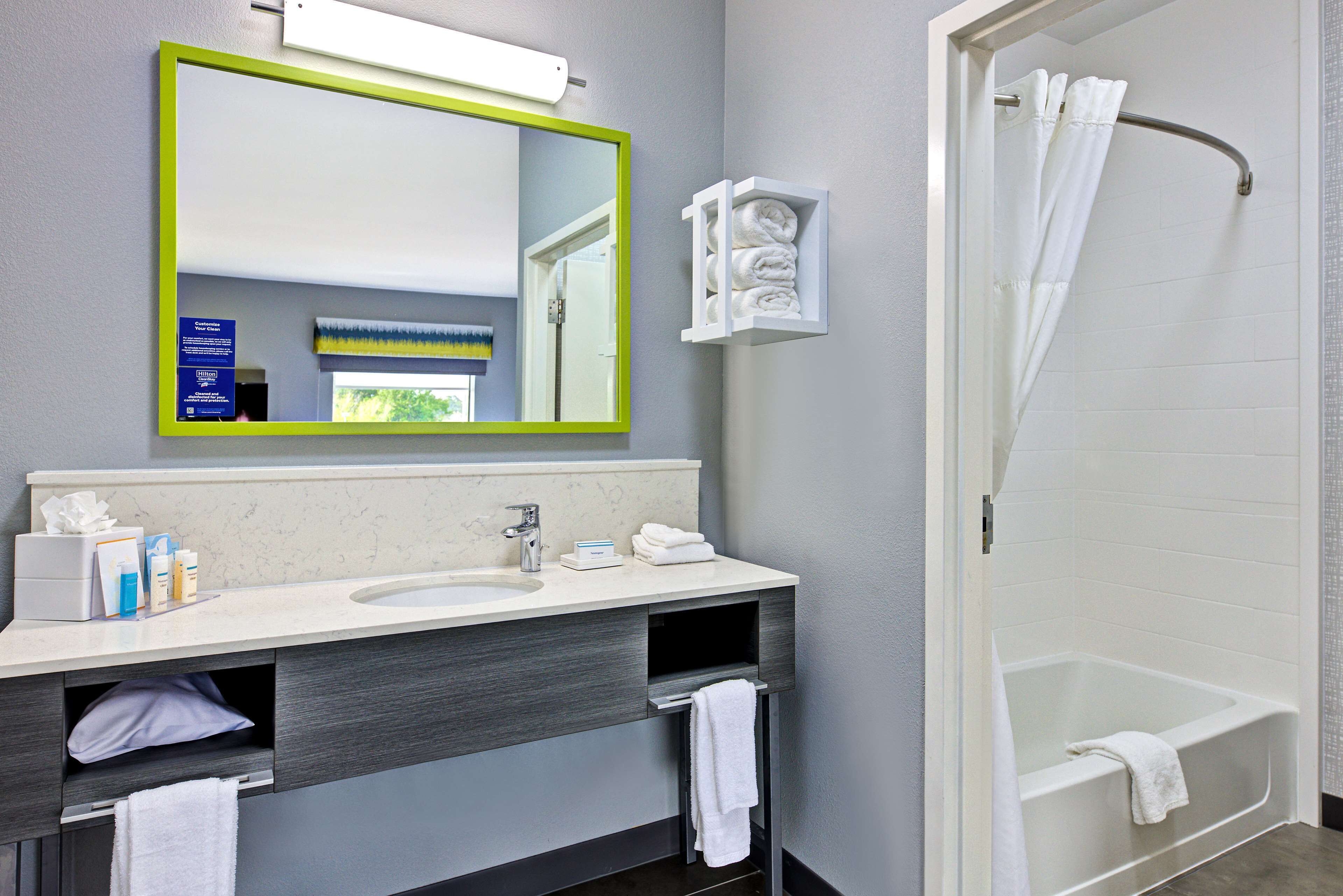 Une salle de bain équipée d’un lavabo, d’un miroir, d’un porte-serviettes et d’une douche.