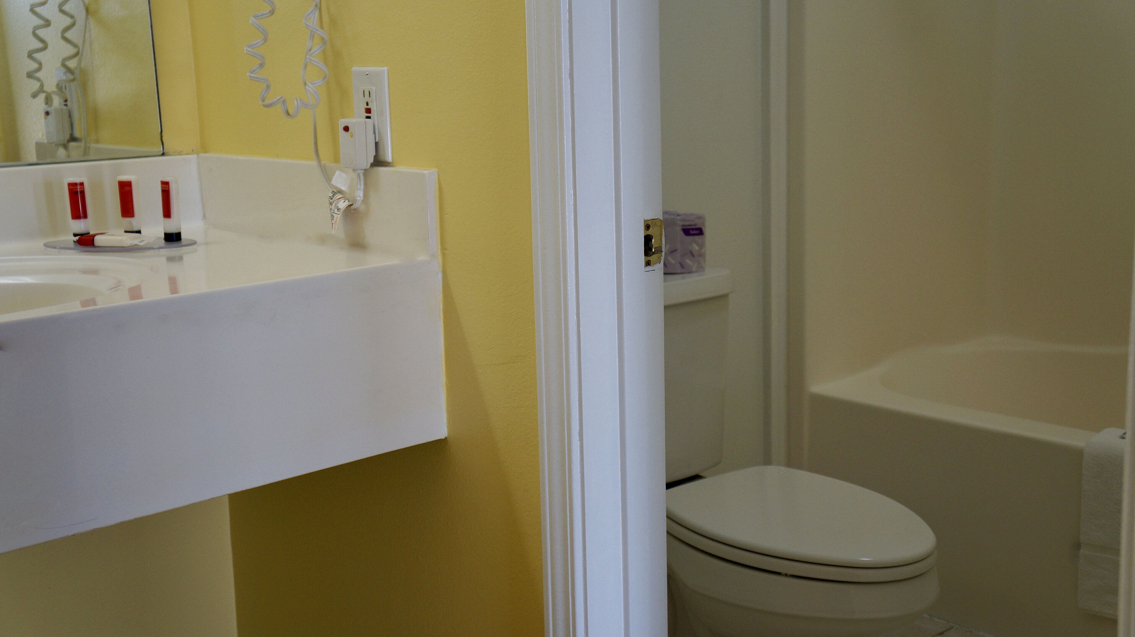 A bathroom with a white sink, mirror, and toilet.