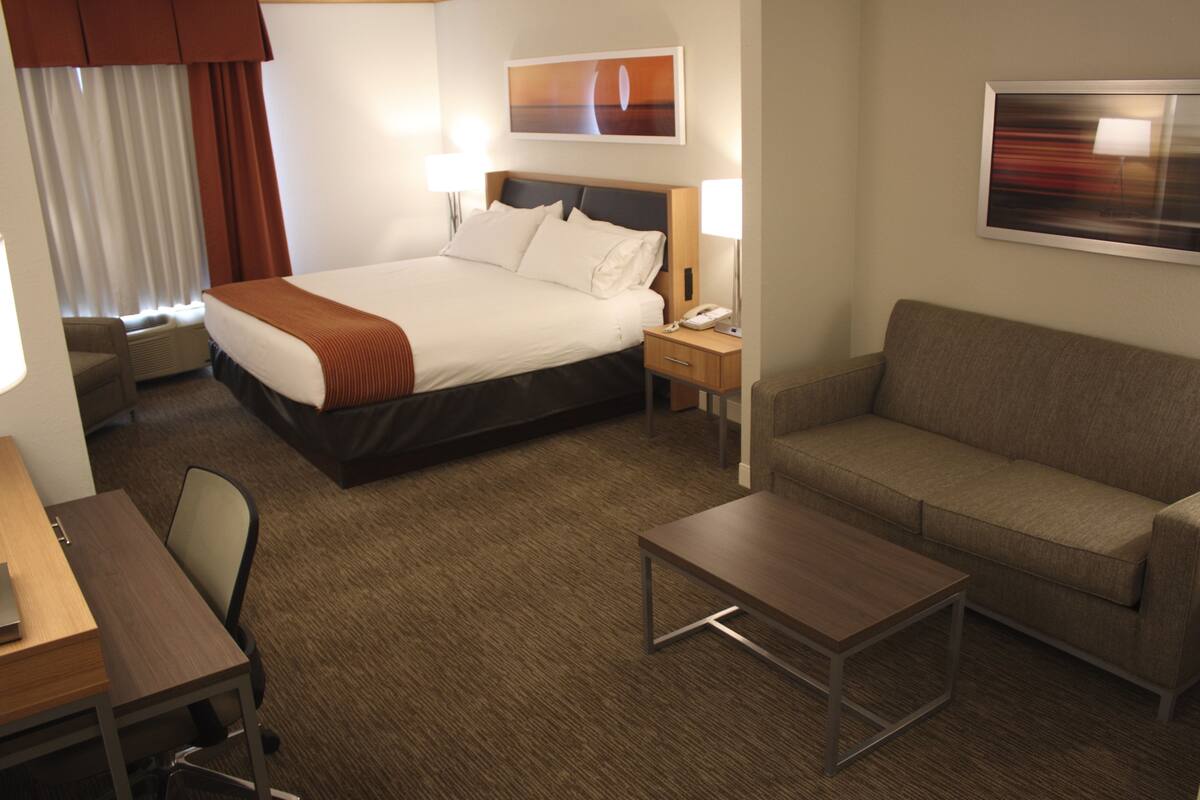 A hotel room with a bed, a sofa, a desk, and a coffee table.
