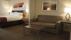 A hotel room with a bed, a sofa, a coffee table, and two bedside lamps. - Holiday Inn Express Munising-Lakeview by IHG (Munising)