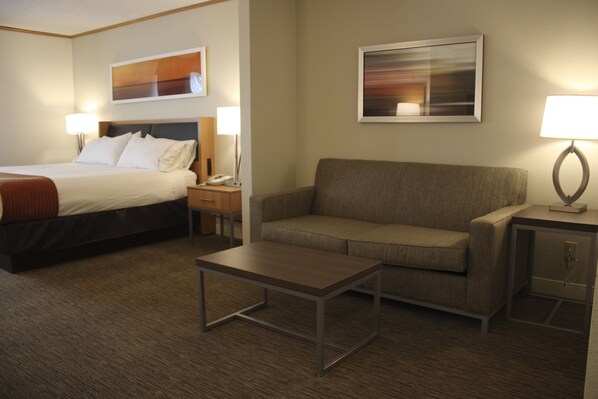 A hotel room with a bed, a sofa, a coffee table, and two bedside lamps. - Holiday Inn Express Munising-Lakeview by IHG (Munising)
