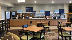 A breakfast area with a self-serve station, seating, and a stone fireplace. - Holiday Inn Express Munising-Lakeview by IHG (Munising)