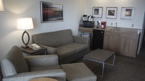 A compact hotel room with a sofa, a small table, a microwave, a coffee maker, and a sink. - Holiday Inn Express Munising-Lakeview by IHG (Munising)