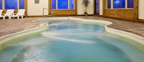 An indoor swimming pool with clear water, surrounded by wooden walls and a tiled floor.