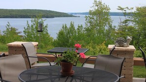 An outdoor patio with a round table, chairs, a potted plant, and a statue. - Holiday Inn Express Munising-Lakeview by IHG (Munising)