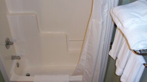 A bathroom with a bathtub, a shower curtain, and a towel rack with towels. - Holiday Inn Express Munising-Lakeview by IHG (Munising)