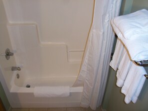 A bathroom with a bathtub, a shower curtain, and a towel rack with towels. - Holiday Inn Express Munising-Lakeview by IHG (Munising)