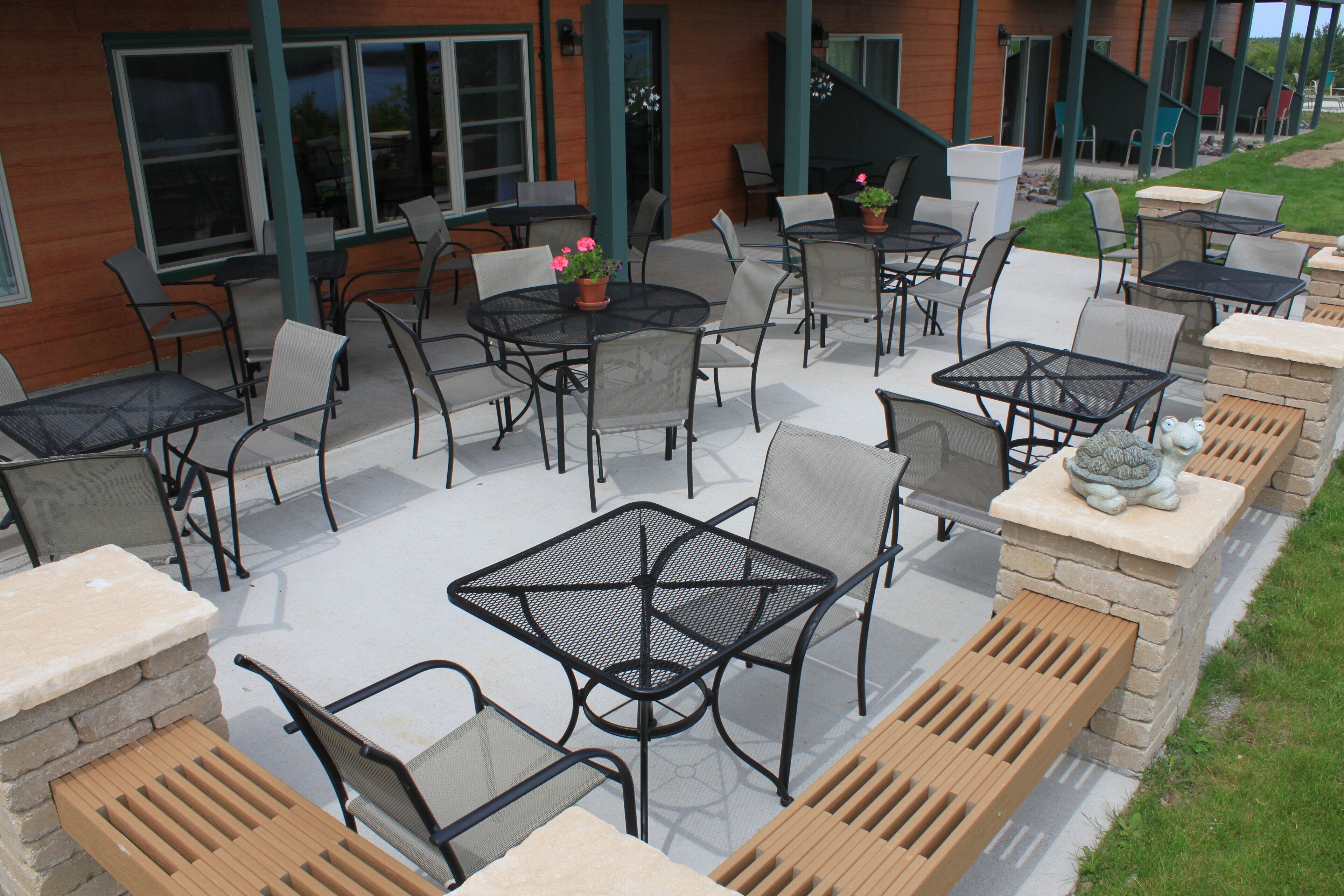 Ein Terrassenbereich im Freien mit mehreren Tischen und Stühlen, einige davon mit Kissen.