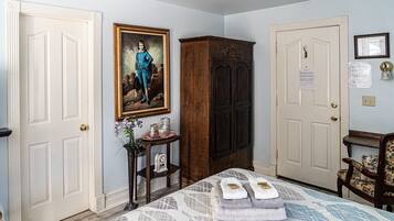 A bedroom with a bed, a dresser, a nightstand, a painting, and a door with a notice.