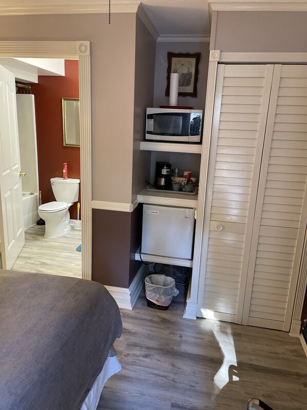 A compact bathroom with a toilet, sink, and a white cabinet with a microwave and coffee maker. - Arrowhead Lake Inn (Lake Arrowhead)
