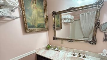 A bathroom with a toilet, sink, vanity, and a painting on the wall.