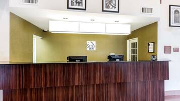 A reception desk with a wooden finish, a sign for Sleep Inn, and two Dell computers.