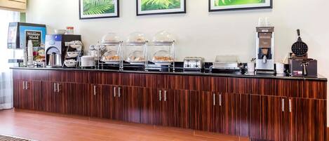 A reception area with a wooden counter, coffee machines, and food display cases.