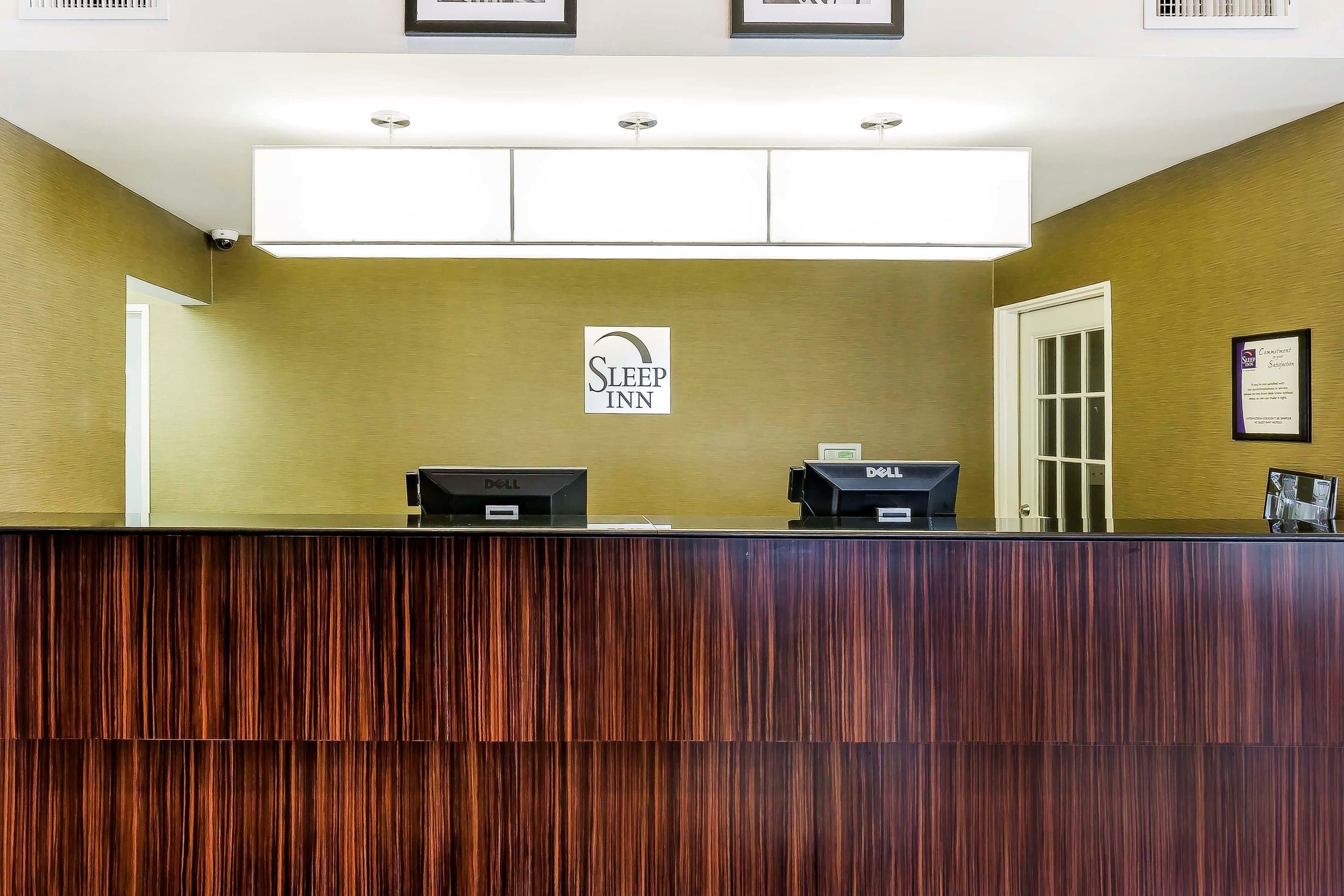 Ein Empfangstresen mit Holzoptik, ein Schild mit der Aufschrift Sleep Inn und zwei Dell-Computer.