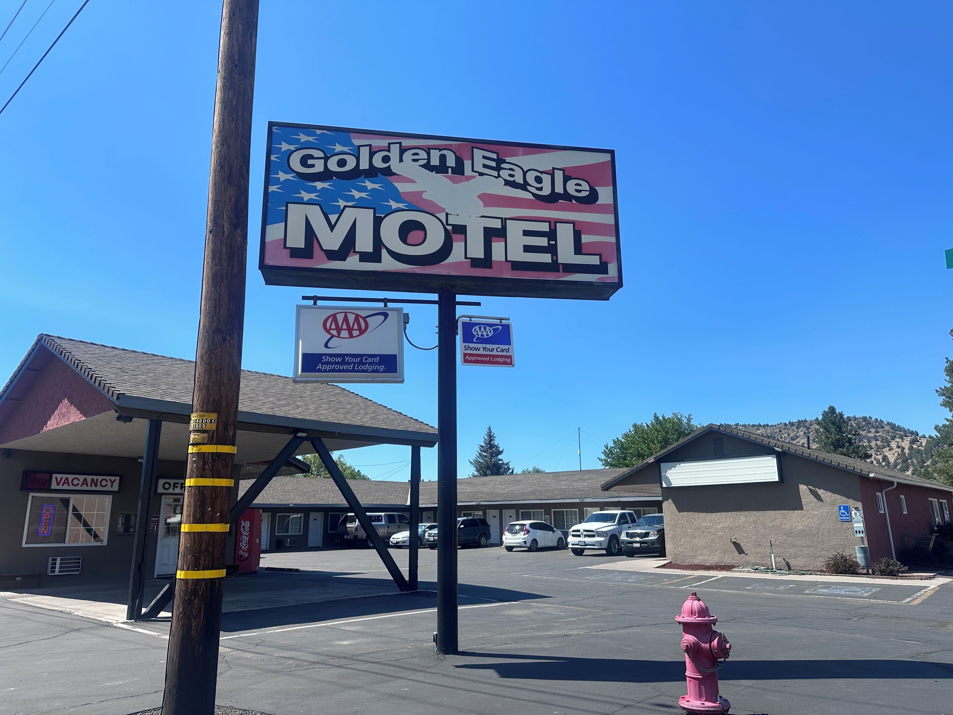 Un motel avec une enseigne bien visible, un parking et un poteau d’incendie.