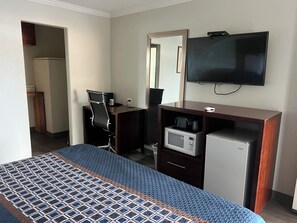 A hotel room with a bed, a desk with a computer, a microwave, a TV, and a small refrigerator. - Golden Eagle Motel (Dorris)