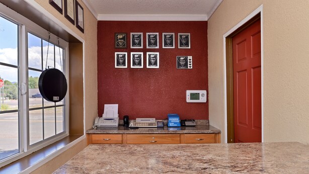 Un área de recepción con mostrador de mármol, una puerta roja y premios enmarcados en la pared.