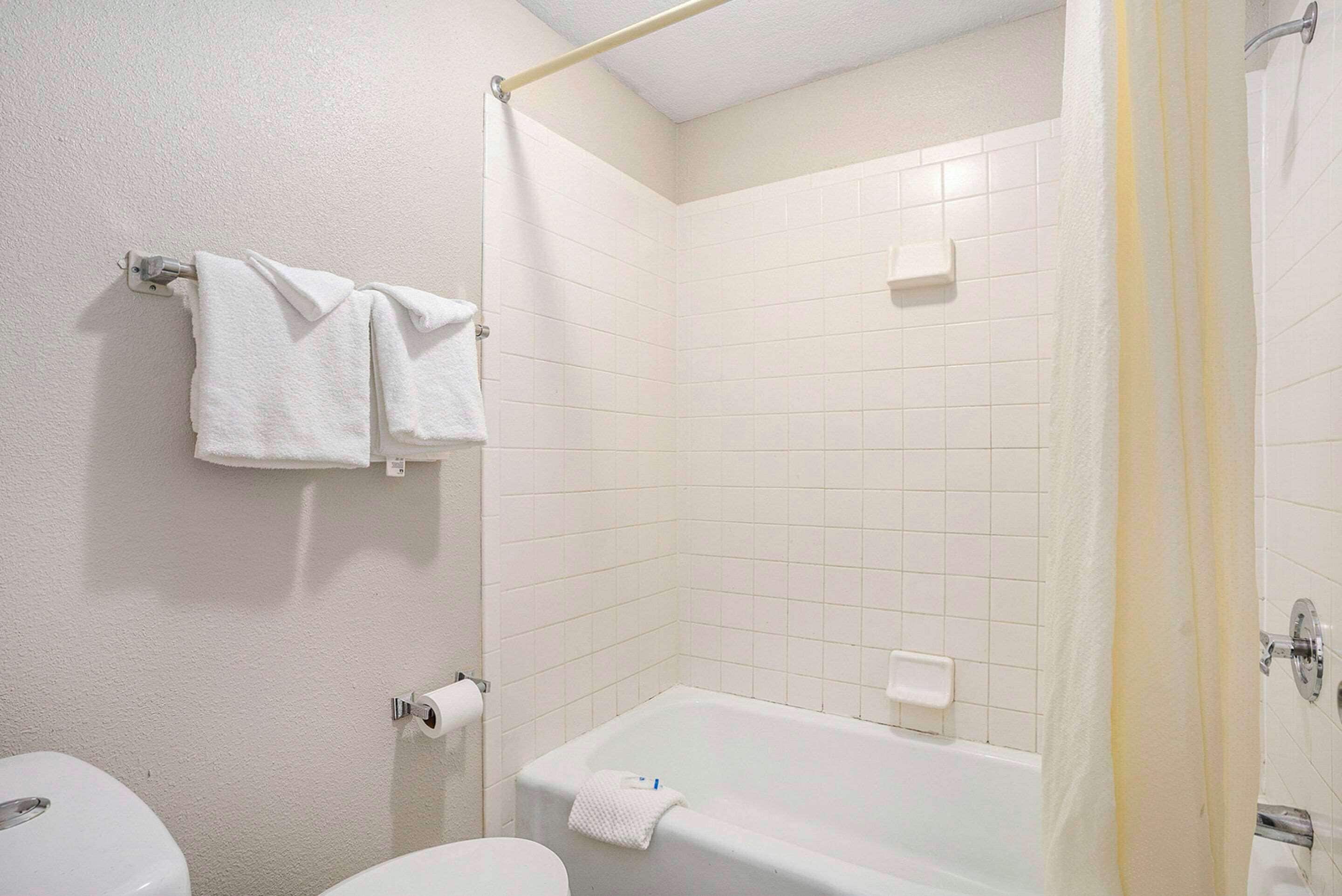A bathroom with a bathtub, toilet, and towel rack.