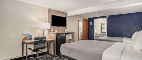 Habitación de hotel con cama, escritorio, computadora, televisor y microondas.