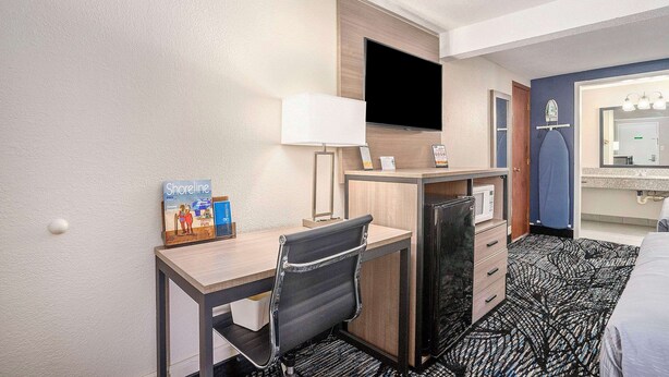 A hotel room with a desk, chair, TV, and a bed. - Rodeway Inn Grand Haven (Grand Haven)