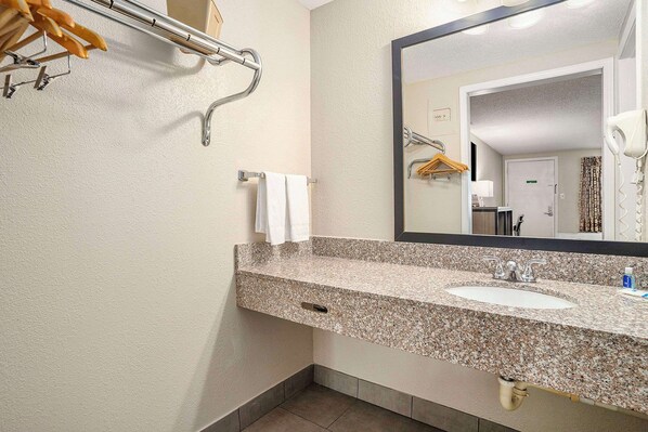 A bathroom with a granite countertop sink, a towel rack, and a mirror. - Rodeway Inn Grand Haven (Grand Haven)