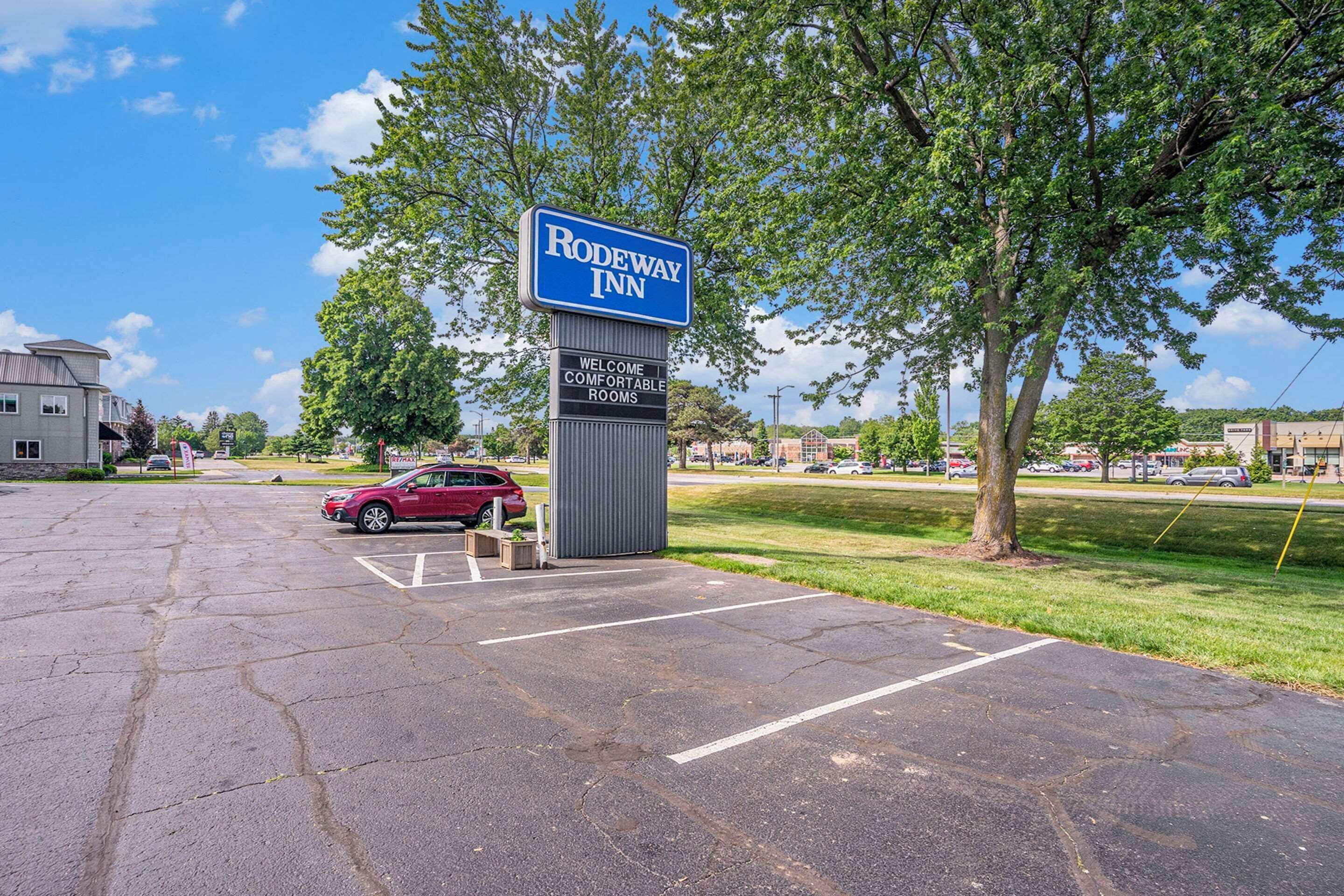 Un parking avec un panneau indiquant la présence d’un hôtel Rodeway Inn, ce qui signifie qu’il propose des chambres confortables.