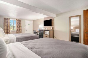 A hotel room with two beds, a desk with a computer, a TV, and a microwave.