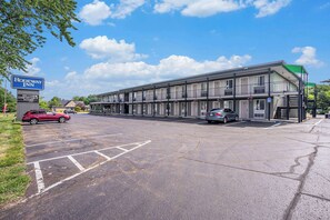 A motel with a signboard, parking lot, and a building with multiple floors and balconies.