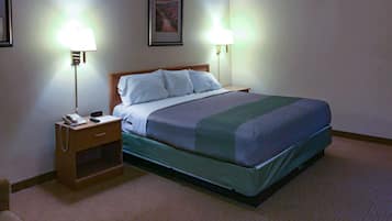 Hotelkamer met een bed, bedlampen, een nachtkastje met een telefoon en een ingelijst schilderij aan de muur.