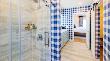 Une salle de bain moderne dotée d’une cabine de douche en verre, d’une douche à l’italienne et de toilettes apparentes.