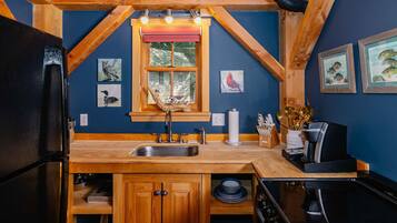Une cuisine avec des meubles de rangement en bois, un évier, une fenêtre donnant sur un beau paysage et une cuisinière.