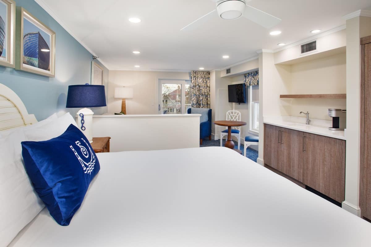 Une chambre d’hôtel avec un grand lit, un bureau, une chaise, une télévision et une salle de bain équipée d’un lavabo et d’un miroir.