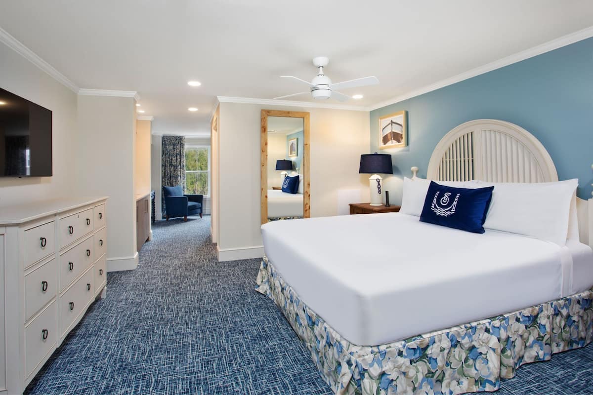 Une chambre d’hôtel avec un grand lit, une commode, un ventilateur de plafond et une vue sur l’extérieur.