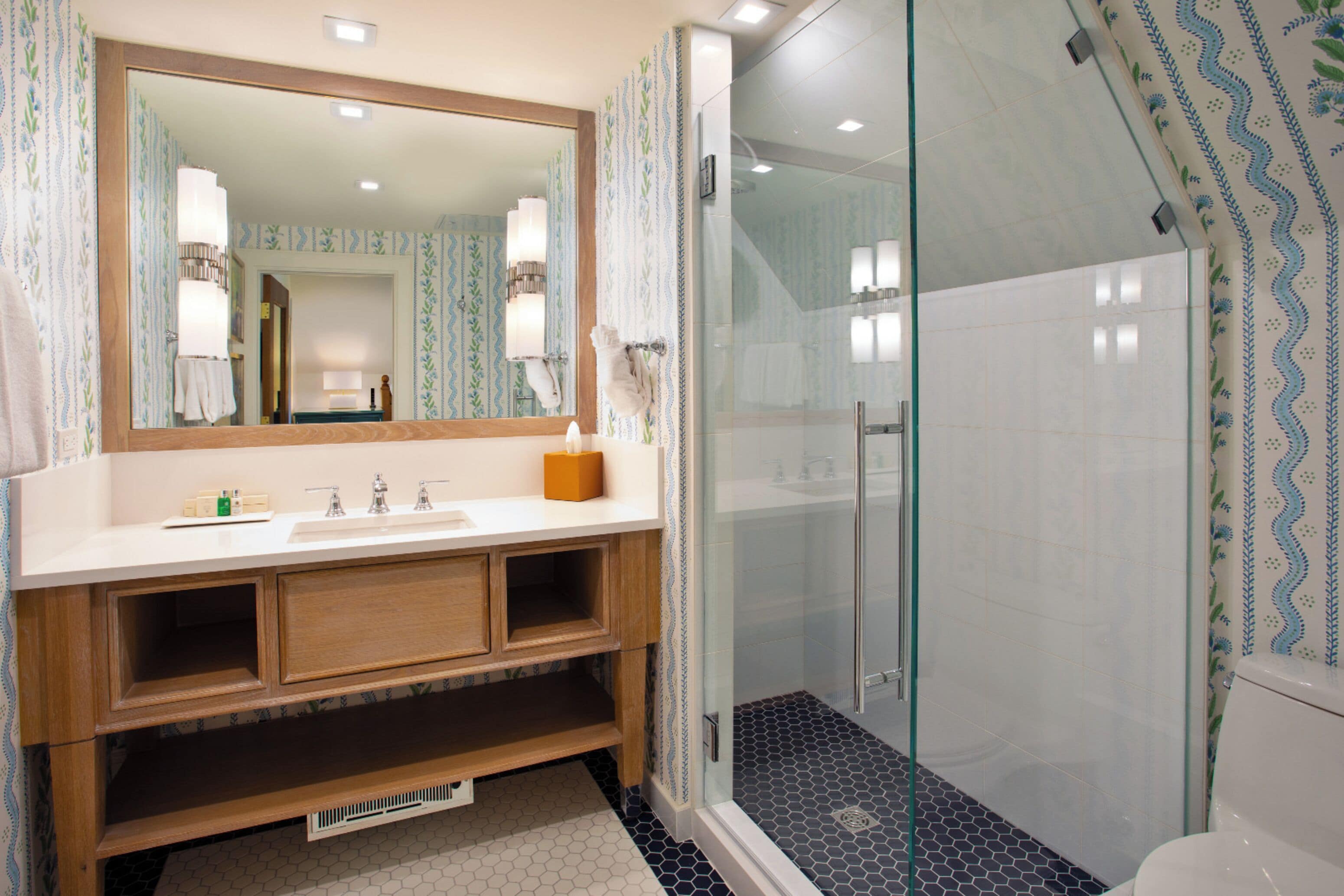 A modern bathroom with a large mirror, wooden vanity, and a glass-enclosed shower.