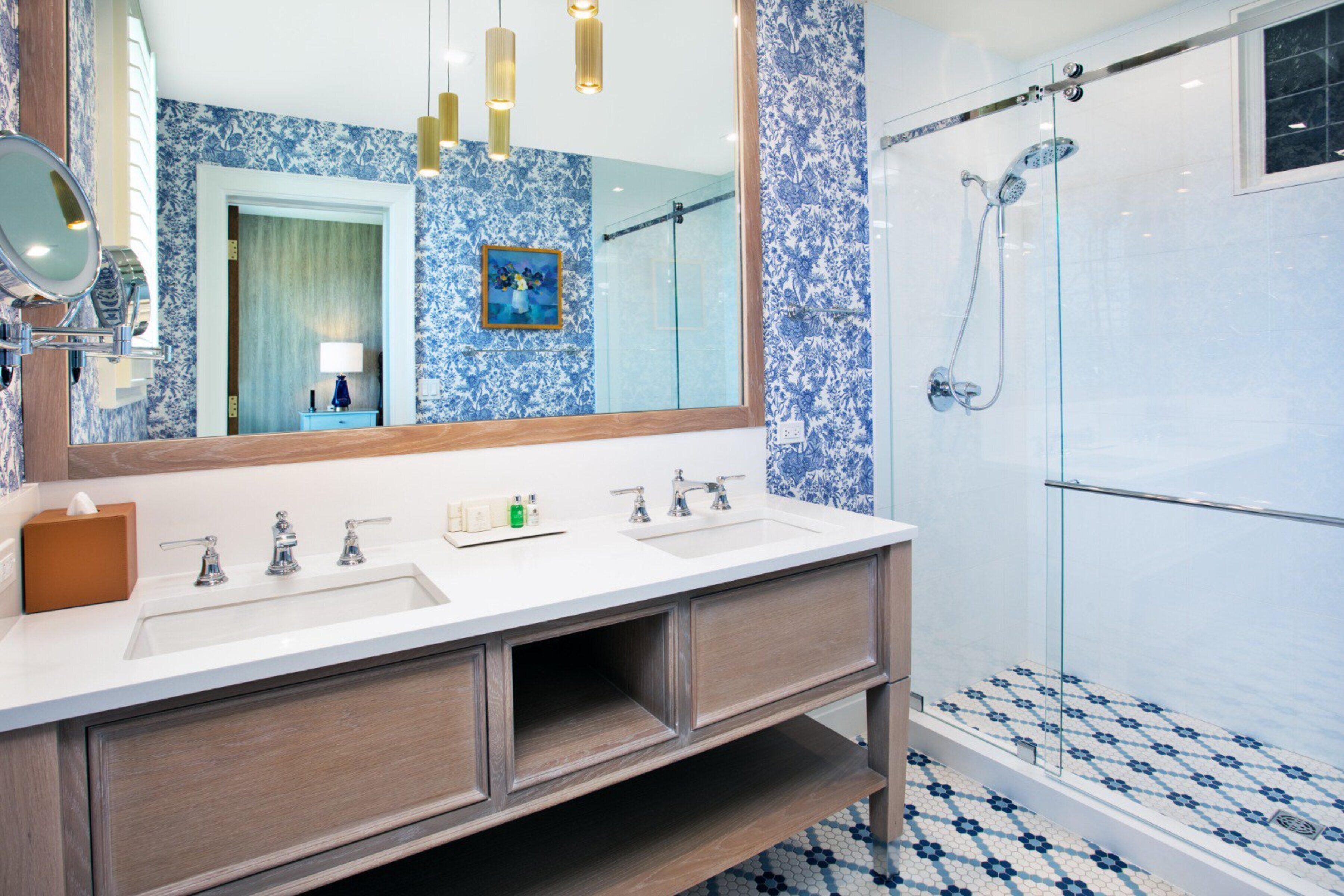 A bathroom with a double sink vanity, a large mirror, and a glass-enclosed shower.