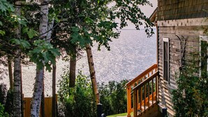 A wooden staircase leading to a deck with a view of a lake and mountains. - The Inn At Stonecliffe (Mackinac Island)