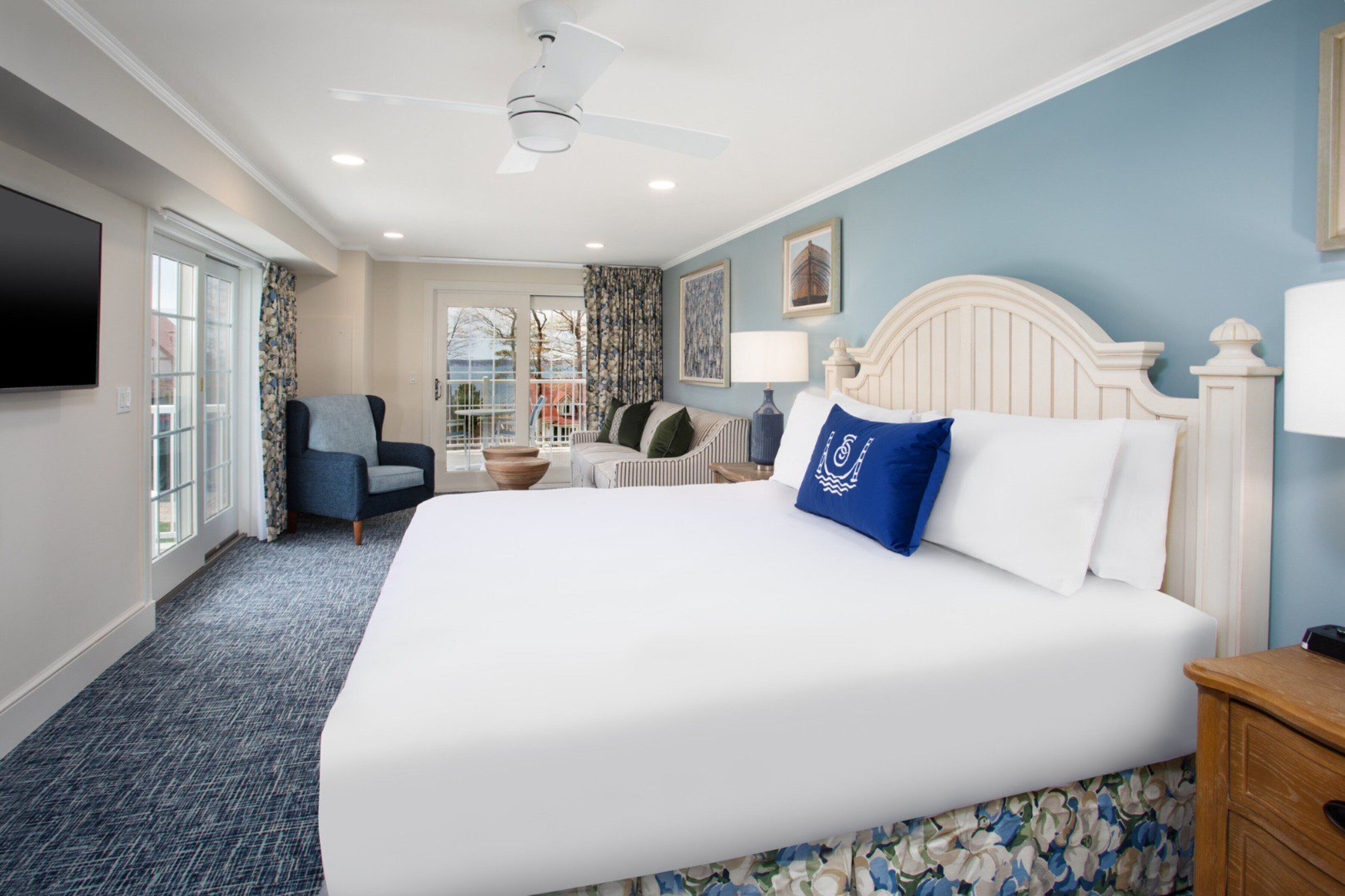 A hotel room with a large bed, a chair, a desk, and a television.